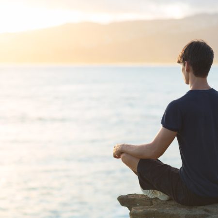 Young,Man,Meditating,On,Top,Ocean,Cliff,During,Sunset.